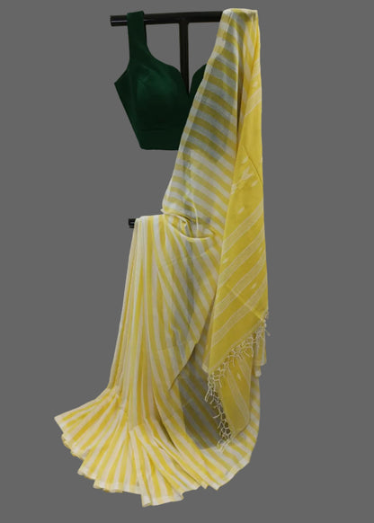 Yellow and white striped cotton saree draped on a black hanger stand, paired with a dark green sleeveless blouse, set against a draped white fabric backdrop.