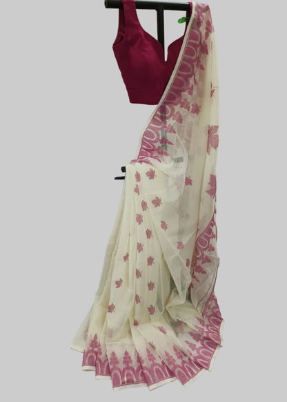 A cream-colored georgette saree with pink floral motifs and a pink border, paired with a solid magenta pink sleeveless blouse, displayed on a hanger against a draped white fabric backdrop.