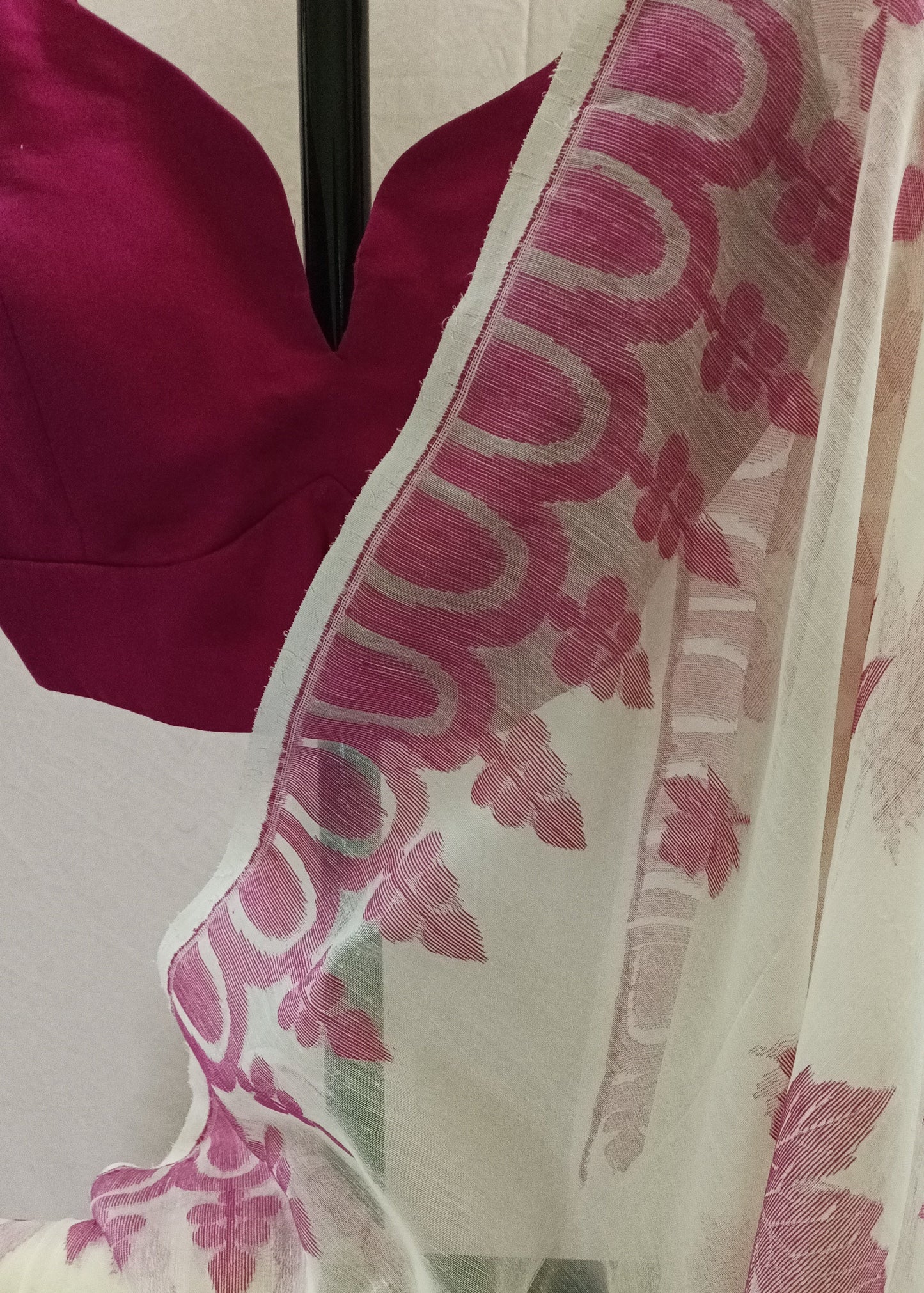 White semi-sheer saree with pink floral block prints and a matching pink blouse displayed on a mannequin.