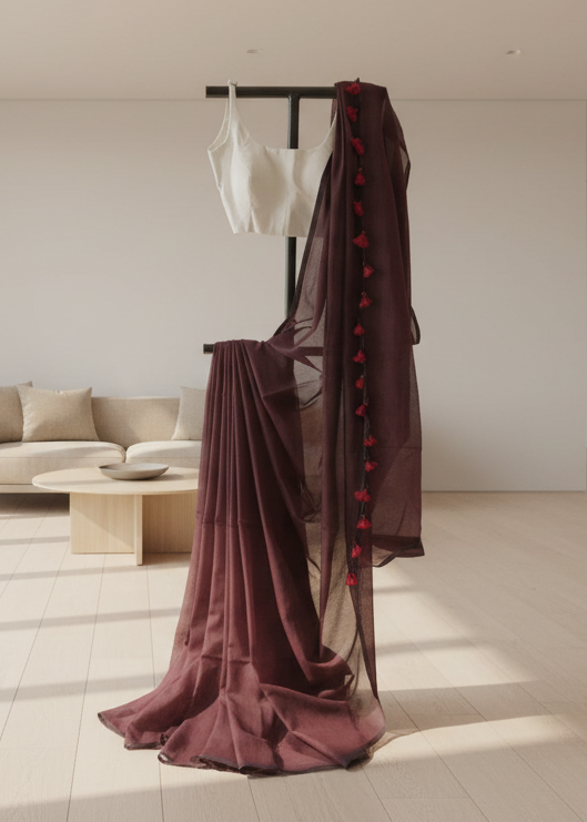 Brown saree with red details on a stand in a room with a sofa and coffee table.