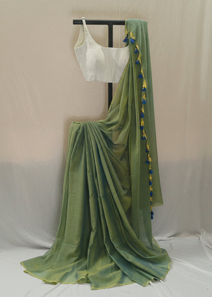 Green saree with a white blouse on a stand against a plain background