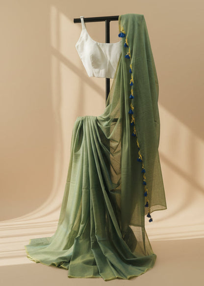 Green saree with a white blouse on a mannequin against a beige wall.