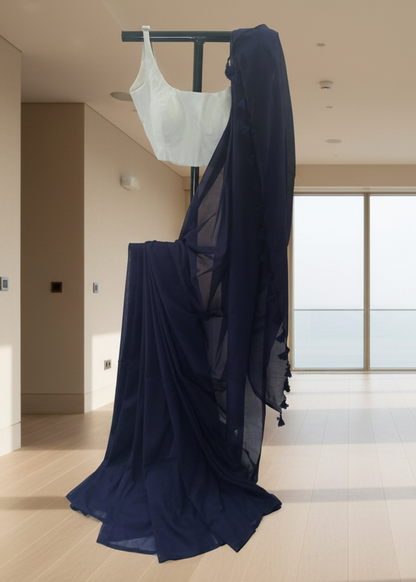 Navy blue sheer fabric draped over a white garment on a hanger in a room with large windows.