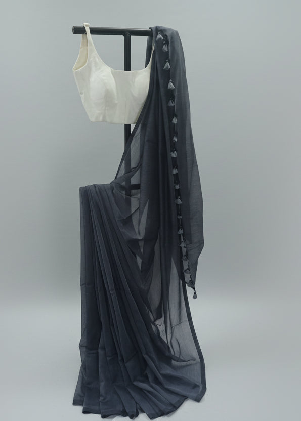White crop top and dark gray skirt with sheer overlay on a stand against a plain background