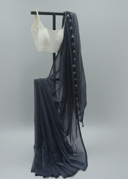 White crop top and dark gray skirt with sheer overlay on a stand against a plain background