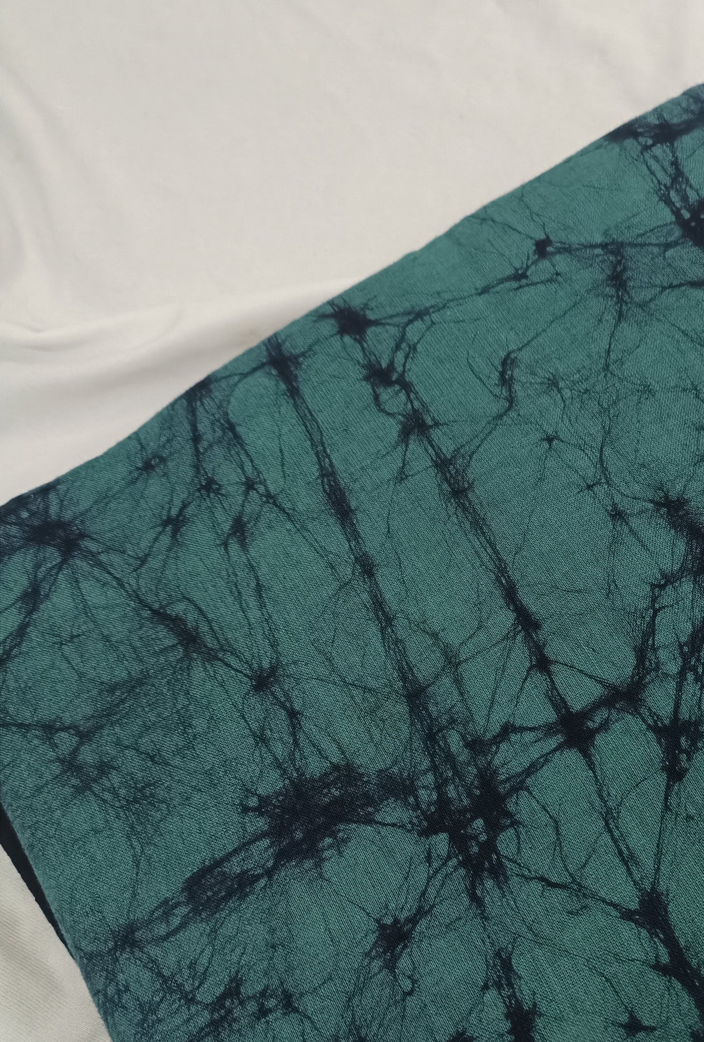 Teal fabric with black tie-dye pattern on a white background