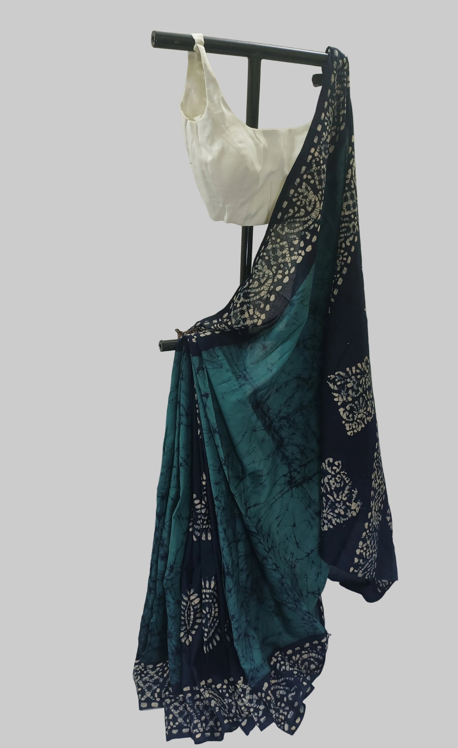 Teal saree with black floral patterns on a white background