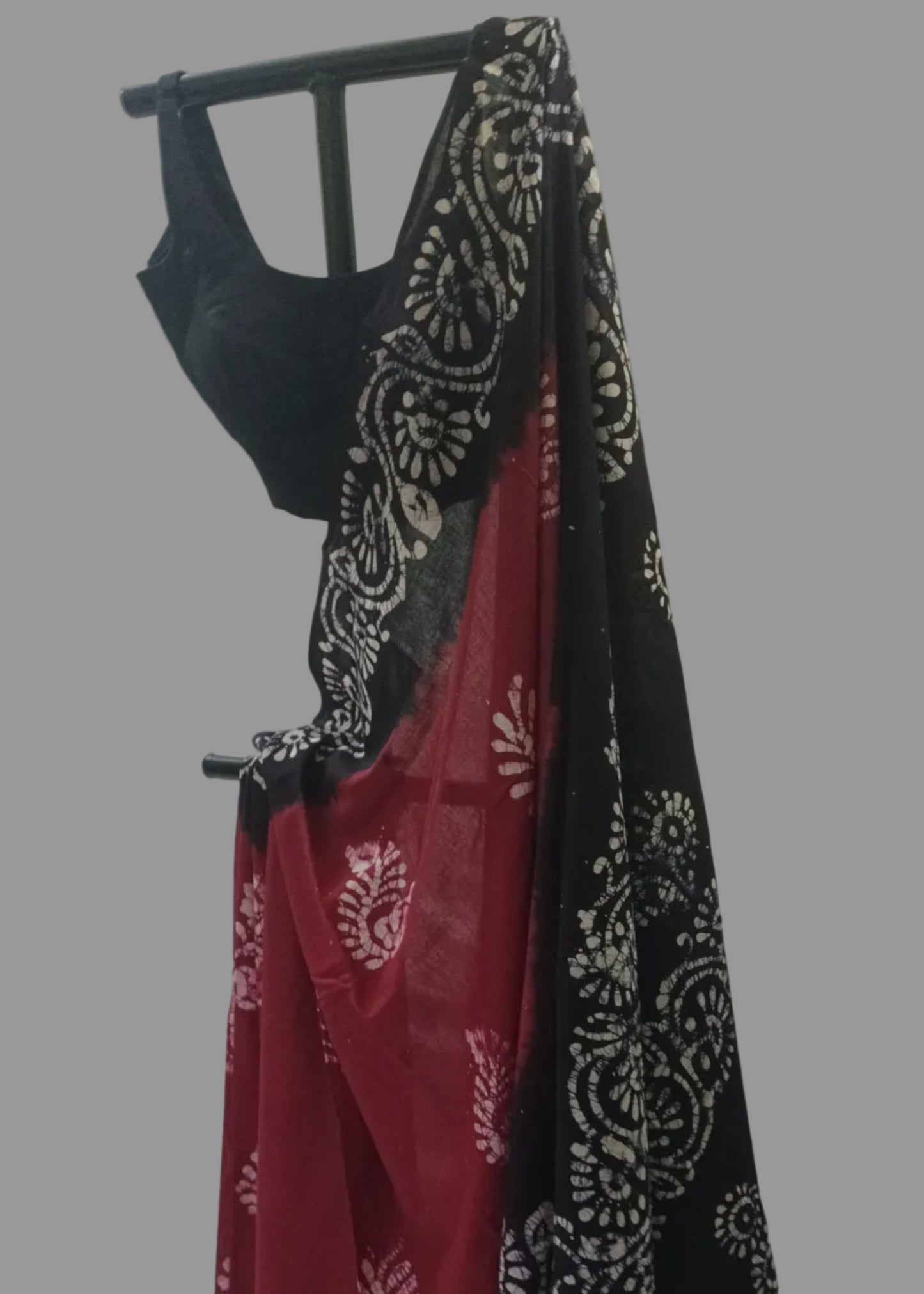 Black and red patterned fabric draped over a black rod against a white curtain background