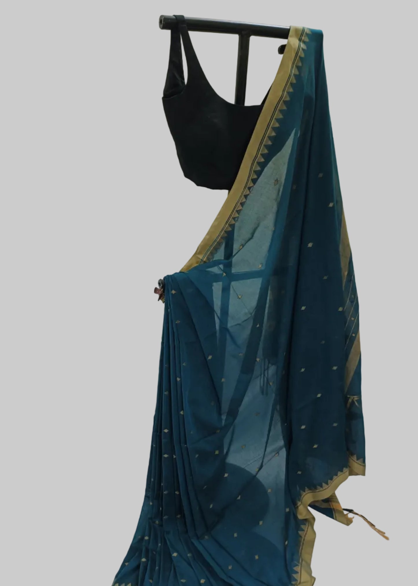 Teal saree with gold border draped over a black blouse on a white background