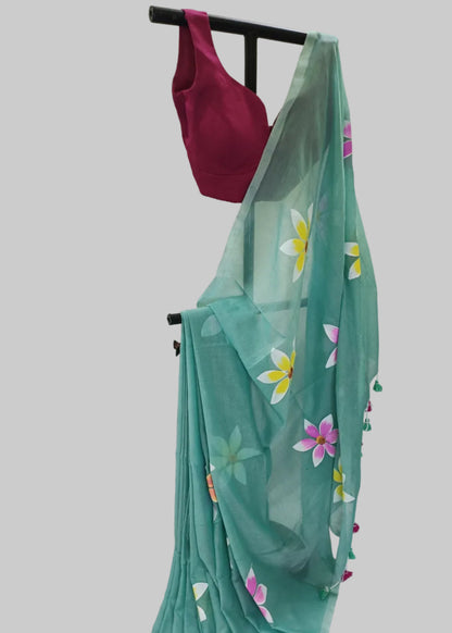 Teal saree with floral patterns and a pink blouse on a white background
