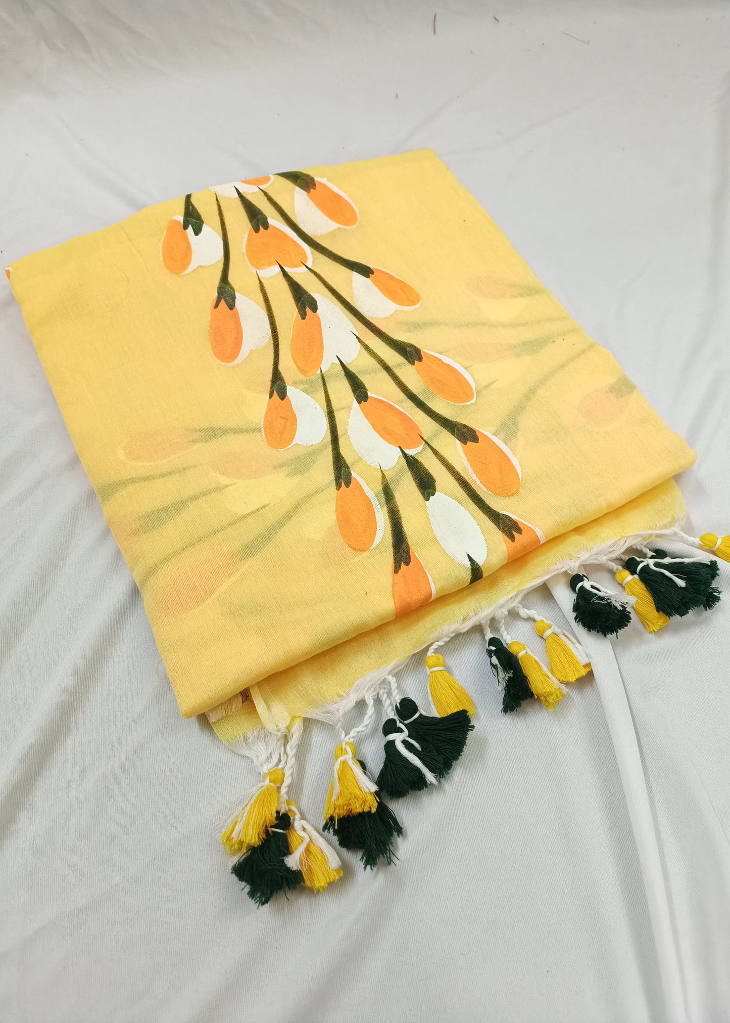 Yellow saree with floral pattern and tassels on a white background