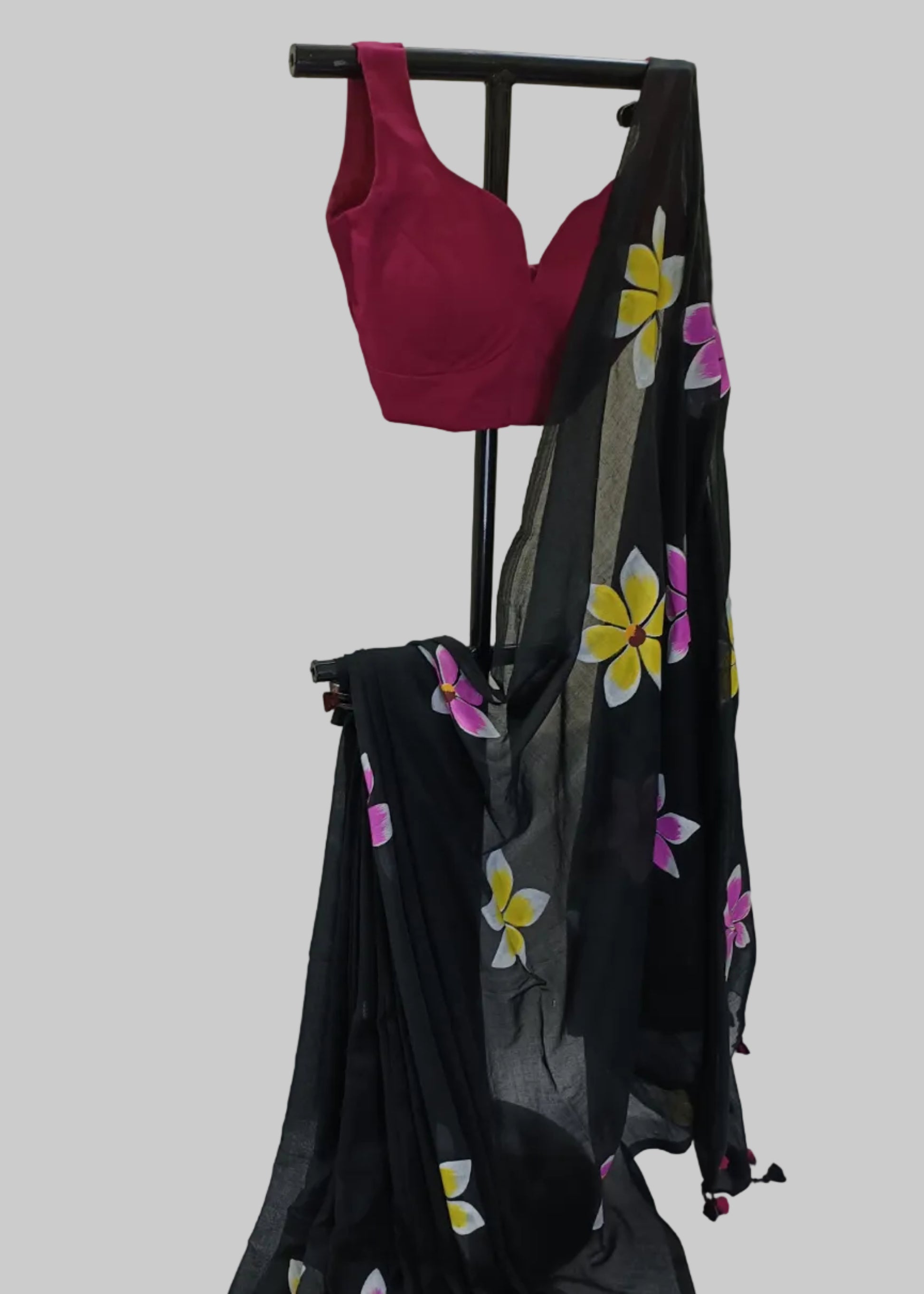 Black saree with floral patterns draped over a stand against a white background