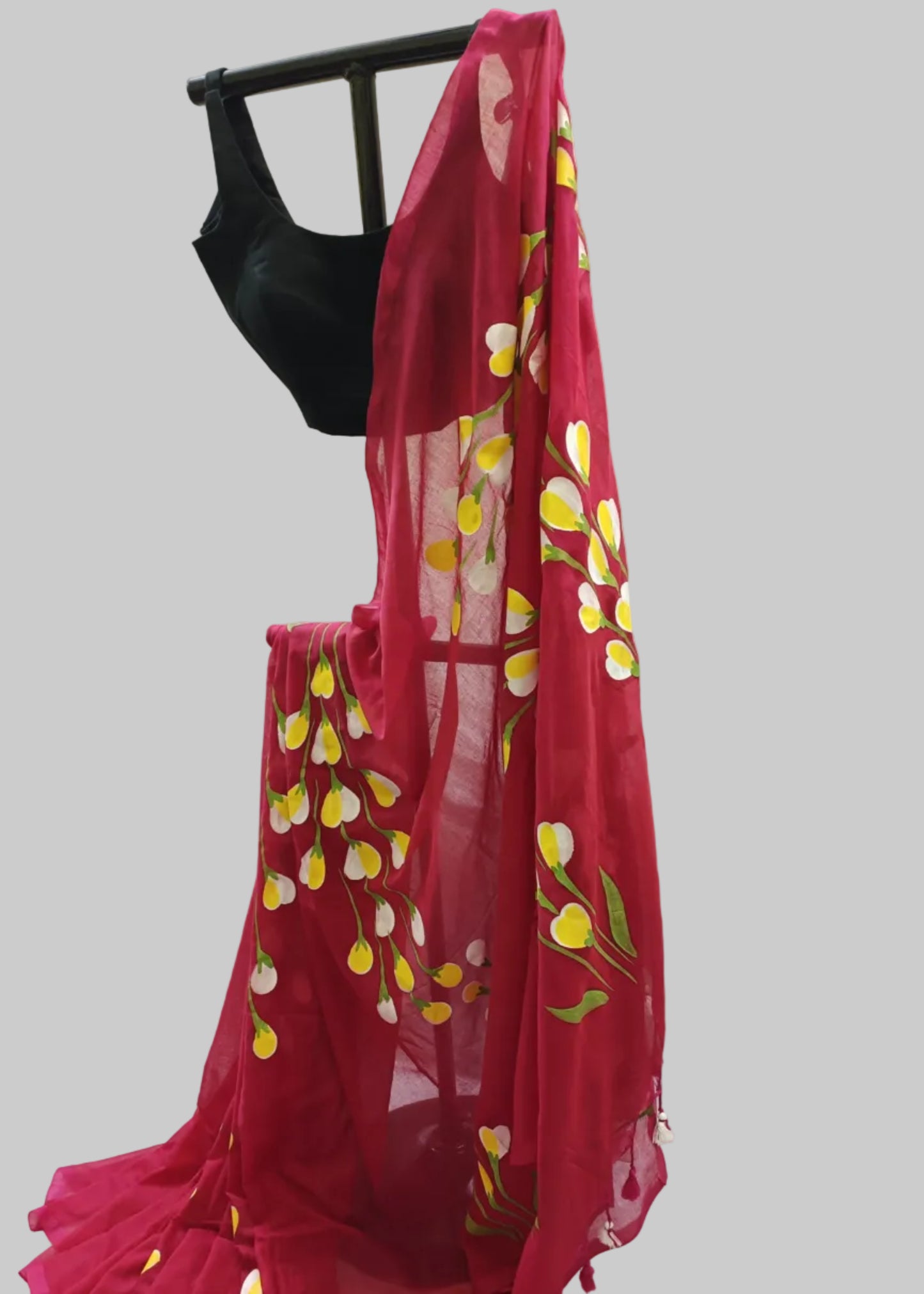Red saree with floral patterns draped over a black blouse on a white background