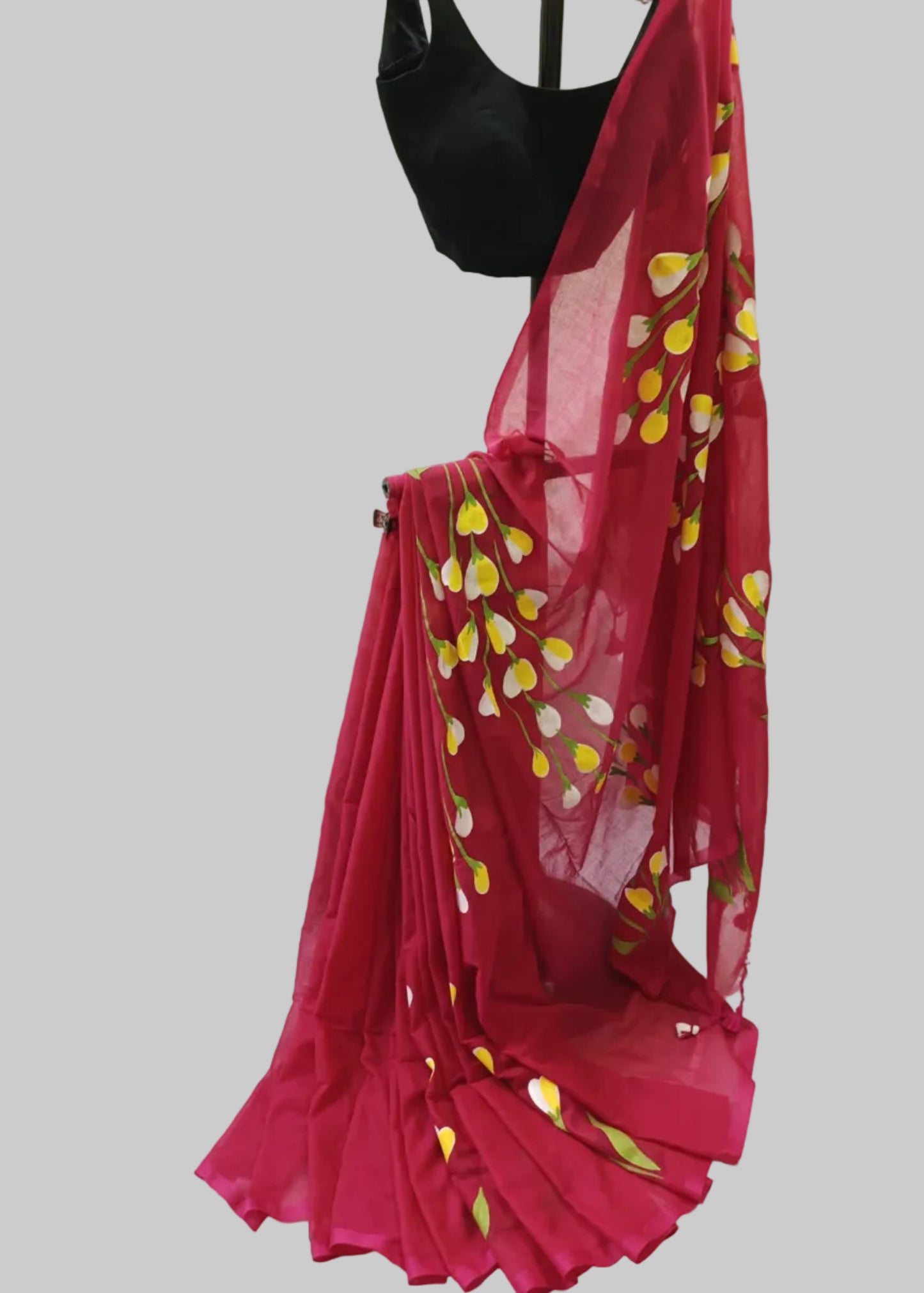 Red saree with yellow patterns draped over a black blouse on a white background