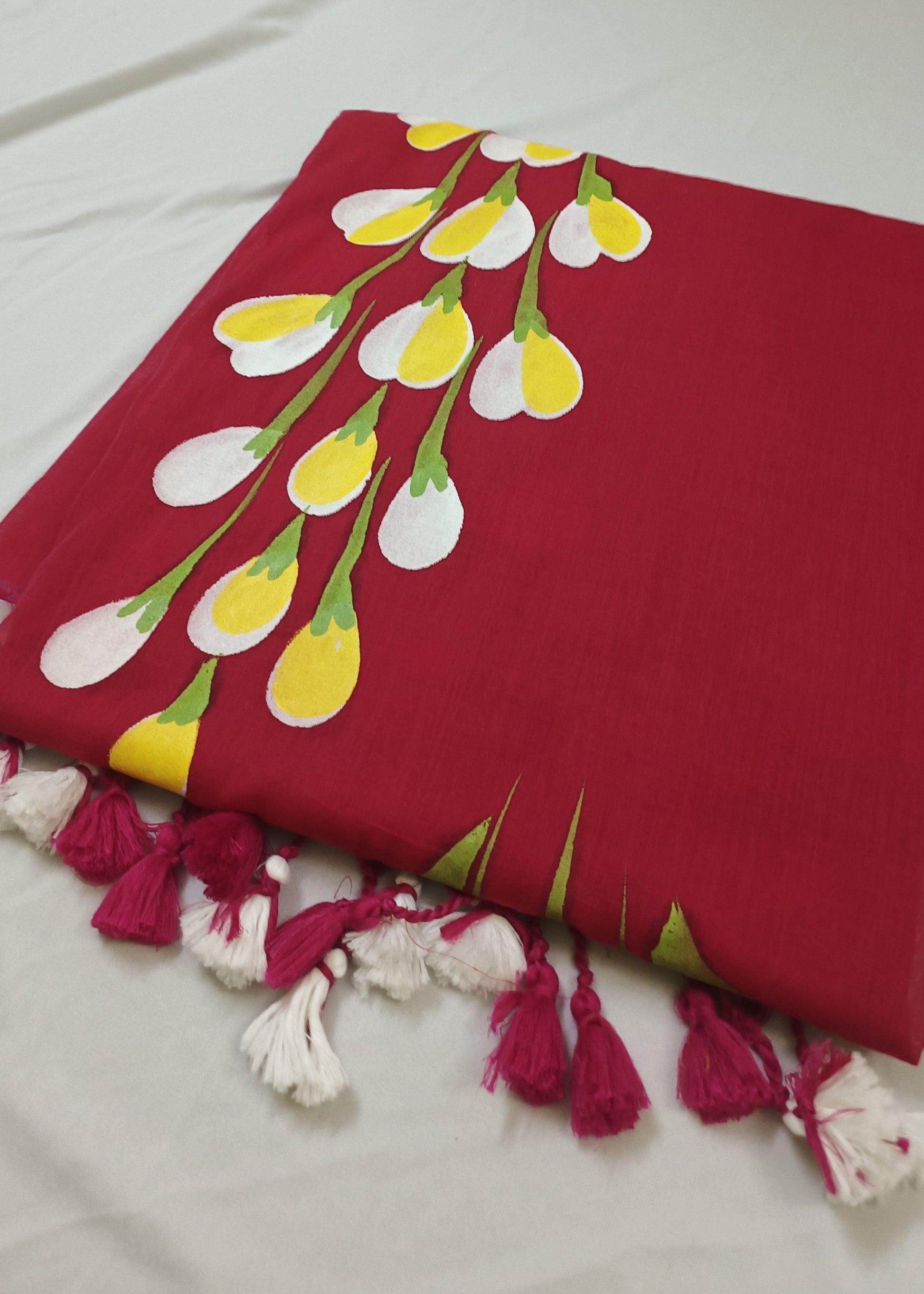 Red fabric with floral pattern and tassels on a white background