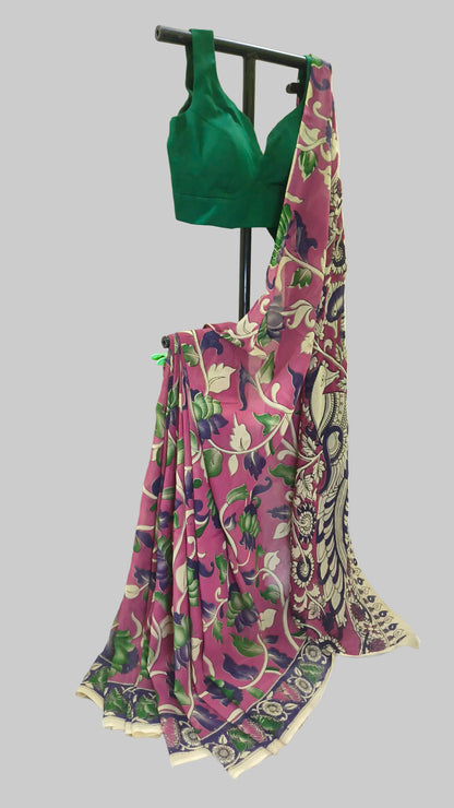 A pink floral printed saree with a green blouse displayed on a black clothing stand against a white backdrop.