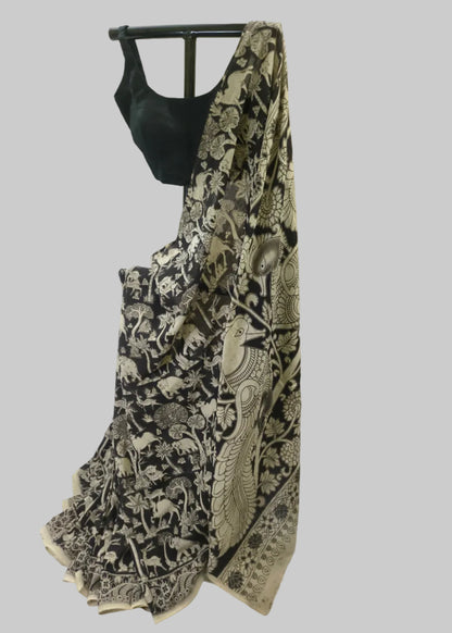 A black sleeveless blouse paired with a black saree featuring an intricate beige and brown animal and floral block print, displayed on a black dress form against a draped cream fabric backdrop.