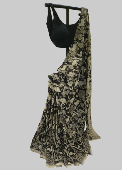 A black saree with beige animal and floral block prints, paired with a solid black blouse, displayed on a black clothing hanger against a draped white fabric backdrop.