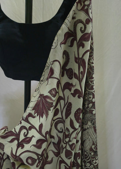 A draped saree or fabric panel with a cream base and dark burgundy floral vine pattern, displayed on a black dress form against a light neutral backdrop.