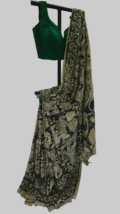 A traditional Indian saree with a black and beige floral block print, draped on a black clothing stand alongside a solid dark green blouse.