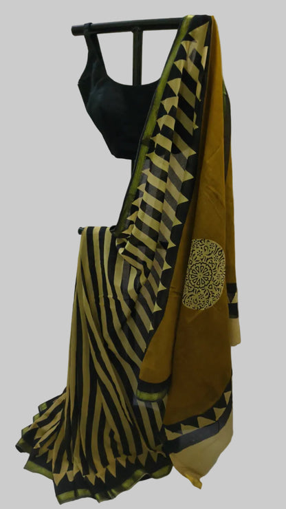 A black and mustard yellow striped saree draped on a black hanger with a black sleeveless blouse, set against a white fabric backdrop.