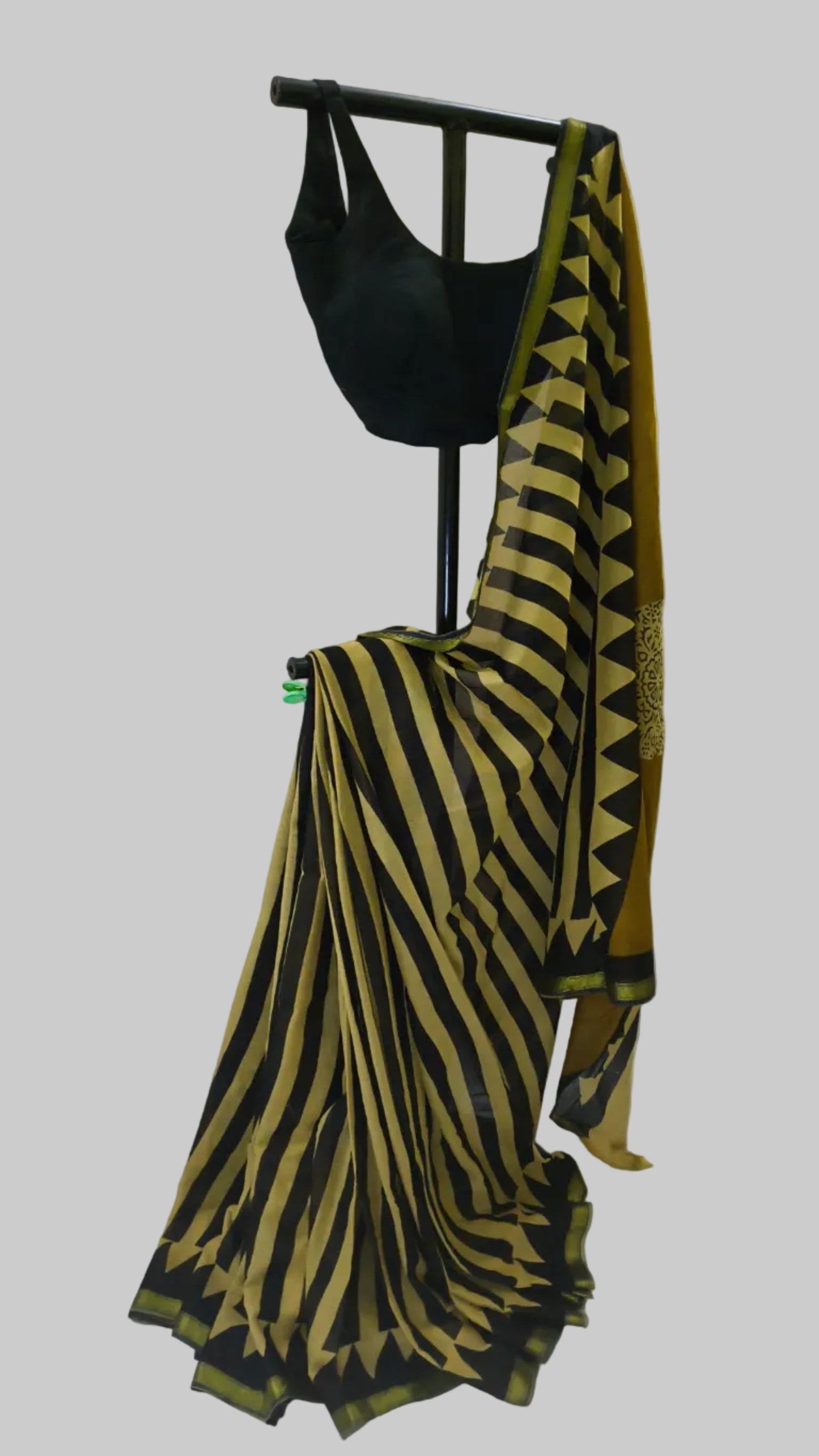 A black and mustard yellow striped saree with a matching black blouse displayed on a black dress form against a white fabric backdrop.