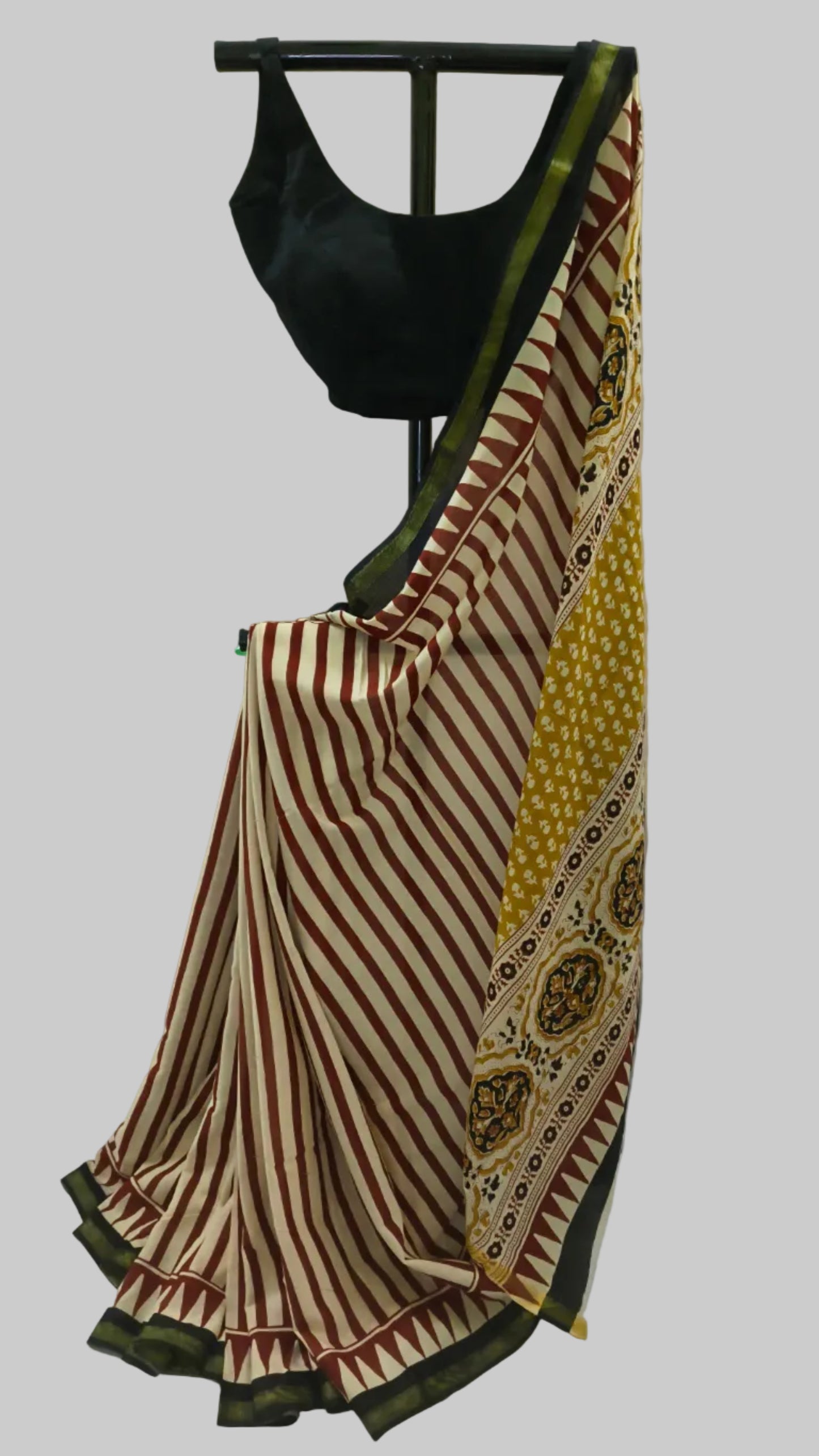 A traditional Indian saree draped on a black hanger with a black blouse, featuring red and cream stripes, a yellow patterned border, and a dark green pallu.