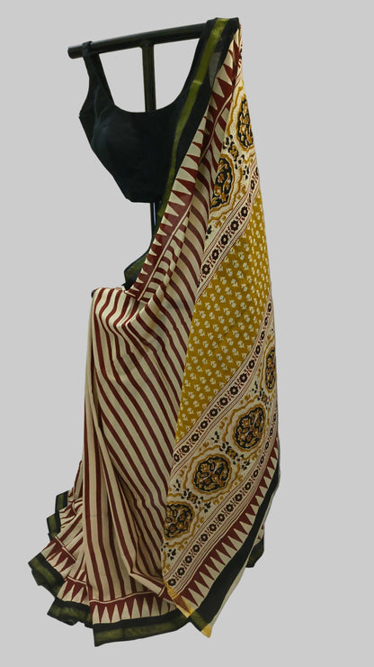 A patterned Indian saree draped on a black hanger with a black blouse, set against a draped white fabric backdrop.