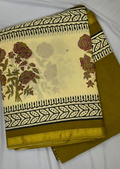 A folded piece of traditional Indian saree fabric, featuring a cream-colored body with a printed floral pattern and borders, paired with a solid mustard yellow border.