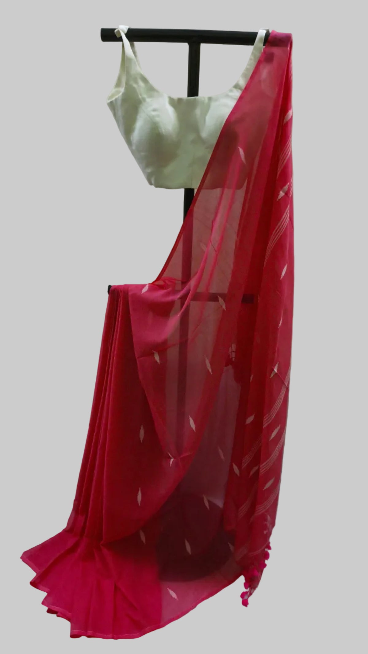 A red georgette saree with white printed motifs and a white blouse, displayed on a black clothing stand against a neutral draped backdrop.
