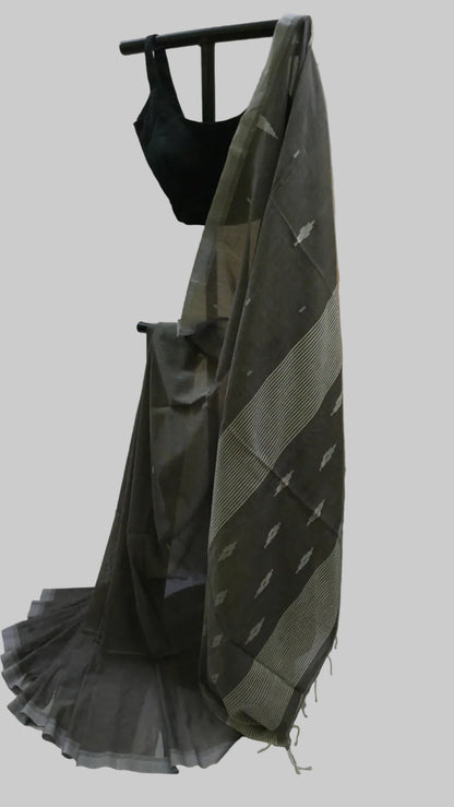 A dark gray and beige patterned saree draped on a black dress form, paired with a black sleeveless blouse, set against a neutral cream-colored fabric backdrop.