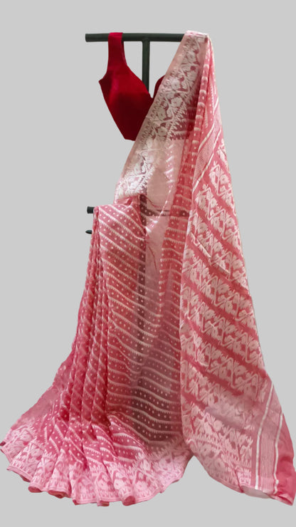 A pink and red patterned saree draped on a black hanger stand, paired with a red sleeveless blouse, set against a draped cream fabric backdrop.