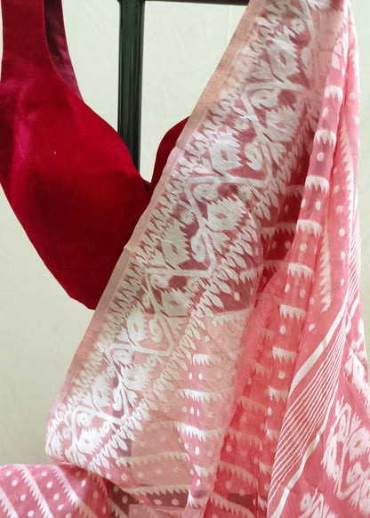 A pink and white patterned saree with a red velvet blouse, draped to show the fabric's intricate ikat and dot motifs.