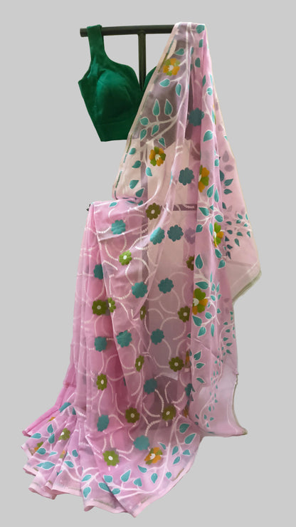A pink saree draped over a black hanger, featuring a white geometric floral pattern with teal and mustard yellow accents, paired with a dark green blouse.