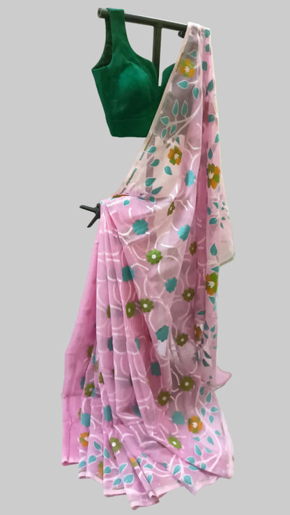 A pink saree with a floral pattern in blue, green, and yellow, draped over a black hanger alongside a dark green blouse, set against a white fabric backdrop.