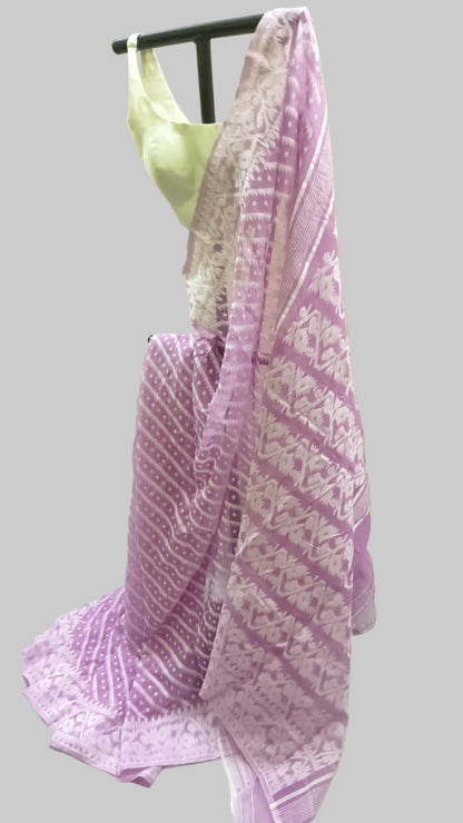 A lavender and white patterned saree draped on a black dress form, with a light green blouse partially visible behind it, set against a cream-colored fabric backdrop.