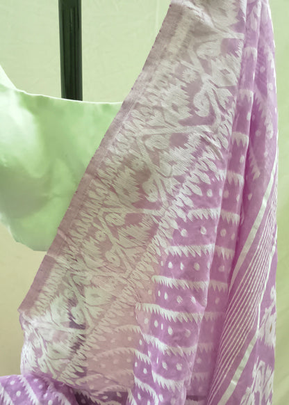 A close-up of a lavender and white patterned saree draped on a mannequin, showing the detailed ikat and tie-dye motifs alongside a light green blouse.