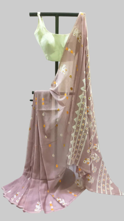 A dusty pink saree with white and orange floral prints and a white border, draped on a black clothing stand with a light green blouse.