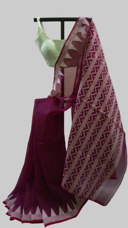 A deep magenta purple saree with a matching printed blouse, draped on a black dress form against a cream-colored fabric backdrop.